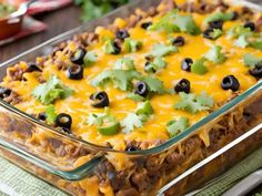 a casserole dish filled with taco meat, cheese and black olives