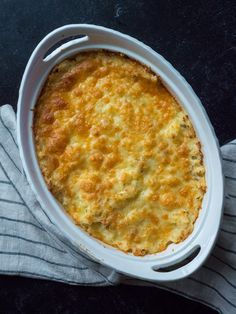 a casserole dish with cheese in it on a napkin next to a fork