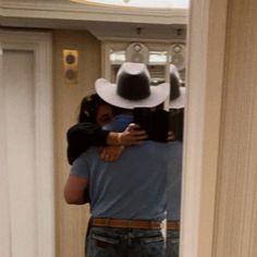 a man in a cowboy hat taking a selfie with his cell phone while standing in front of a mirror