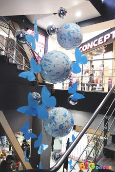 some blue and white balloons hanging from the side of a metal handrail in a mall