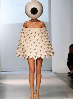 a woman walking down a runway wearing a dress made out of paper