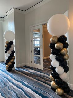 some balloons are on the floor in front of a door and another balloon is hanging from the ceiling