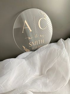 a glass plate with the name and date on it sitting on a white bed sheet