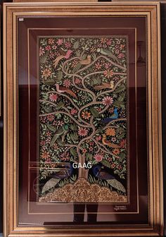 an intricately decorated tree with birds and flowers is framed in a wooden frame on the wall