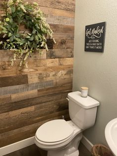 a white toilet sitting next to a sink in a bathroom under a wooden paneled wall