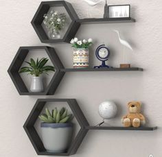 three hexagonal shelves with plants and other items on them against a white wall