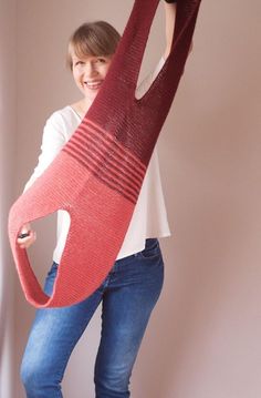 a woman holding up a knitted scarf in the shape of an elephant's tail