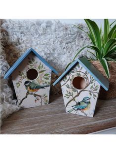 three bird houses sitting on top of a wooden shelf next to a potted plant