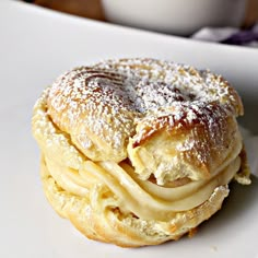 a close up of a pastry on a plate with powdered sugar and coffee in the background