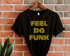 "feel da funk t-shirt in Black  ** MATERIAL ** * 100% combed and ring-spun cotton (Heather colors contain polyester) * Ash color is 99% combed and ring-spun cotton, 1% polyester * Heather colors are 52% combed and ring-spun cotton, 48% polyester * Athletic and Black Heather are 90% combed and ring-spun cotton, 10% polyester * Heather Prism colors are 99% combed and ring-spun cotton, 1% polyester * Fabric weight: 4.2 oz (142 g/m2) * Pre-shrunk fabric * Shoulder-to-shoulder taping * Side-seamed   ** PRODUCT SIZING **  Unisex Shirt Sizing SIZE - LENGTH (inches) - WIDTH (inches) XS     27 inches     16 ½ inches S     28 inches     18 inches M     29 inches     20 inches L     30 inches     22 inches XL     31 inches     24 inches 2XL     32 inches     26 inches 3XL     33 inches     28 inches Retro Black Top With Funny Text, Retro Black Tops With Funny Text, Black Retro T-shirt With Funny Text, Retro Black T-shirt With Funny Text, School Tees, Retro Tee, The 70s, Prism Color, Retro Tshirt