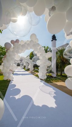 an outdoor ceremony with white balloons in the shape of flowers and trees, on a sunny day