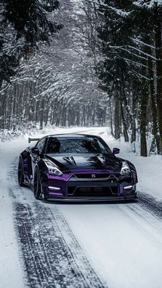 a purple sports car driving down a snow covered road in front of some tall trees