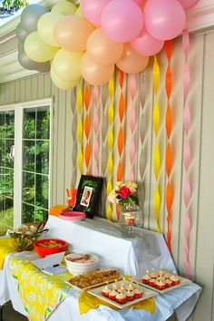 an image of a party with balloons on the wall and food on the table in front of it