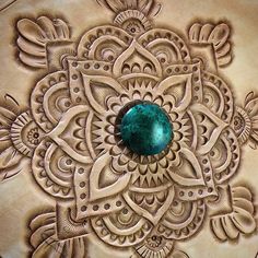 a green stone sitting on top of an intricately designed tablecloth with ornate designs