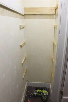 a small room with unfinished shelves and tools in the corner on the floor next to the closet door