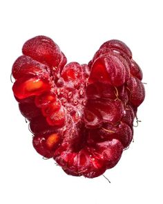 a heart shaped piece of fruit on a white surface with water droplets all over it