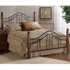 a bed with a metal headboard and foot board in a room next to a potted plant