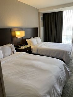 two beds in a hotel room next to each other with lamps on the nightstands