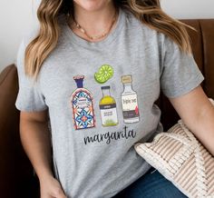 Get ready to party with our fun and trendy margarita shirt! Made with soft and comfortable fabric, this shirt features a vibrant and colorful design of a classic margarita cocktail. Perfect for summer BBQs, beach vacations, and any occasion where you want to add a little bit of flair to your outfit. Made with high-quality materials, this shirt is sure to become one of your favorites. Order now and raise a glass (or a shirt!) to good times and great friends Margarita Shirt, Margarita Recipe Shirt, Tequila Lover Shirt, Classic Cocktail Recipe, Tequila Lover Gift, Tequila and Tacos Shirt, Tequila Overview -These t-shirts have-ribbed knit collars to bolster shaping. -The shoulders have taping for better fit over time. -Dual side seams hold the garment's shape for longer. -100% Airlume combed a Fun Short Sleeve Tops For Cinco De Mayo, Fun Cotton Tops For Cinco De Mayo, Fun Graphic Print Tops For Cinco De Mayo, Fun Cinco De Mayo Tops With Funny Print, Fun Tops With Funny Print For Cinco De Mayo, Fun Cinco De Mayo Funny Print Tops, Margarita Shirt, Womens T Shirts, Classic Cocktail Recipes