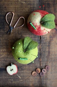 two apples are sitting next to each other on a table with sewing pins and scissors