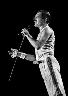 a black and white photo of a man holding a microphone in his right hand while singing