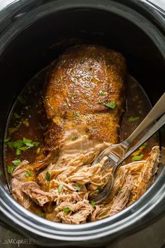 a slow cooker filled with meat and garnished with parsley