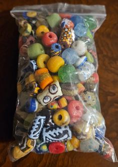 a bag filled with lots of different colored donuts on top of a wooden table