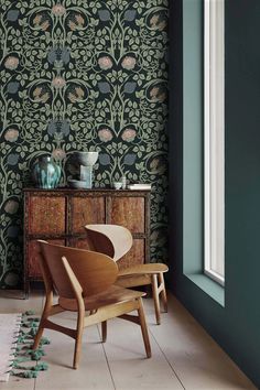 a chair and table in front of a wallpapered room with flowers on it