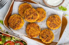 four crab cakes sitting on top of a plate next to a bowl of ranch dressing