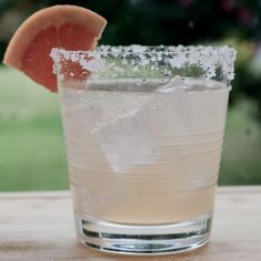 a close up of a drink with a slice of grapefruit on the rim