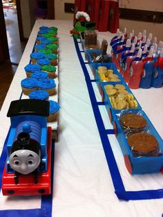 a table with cupcakes, cookies and thomas the tank engine train on it