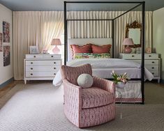 a bedroom with four poster bed, pink chair and white dresser in the corner next to it