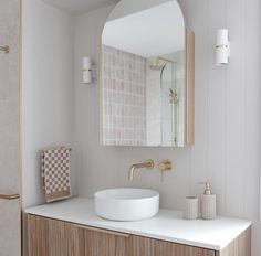 a white sink sitting under a bathroom mirror