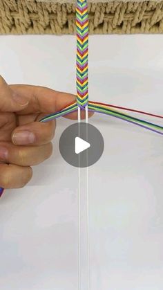 a person is holding a piece of paper with colored wires attached to it and pointing at the end