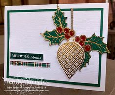 a christmas card with holly leaves and a gold ornament hanging from it's side