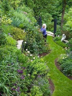 a woman walking through a lush green garden