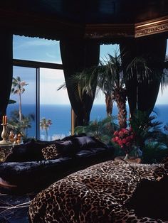 a leopard print bed sitting in front of a large window next to a palm tree