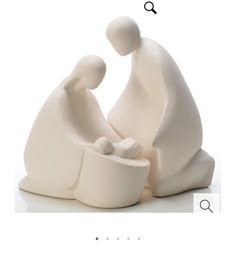 two white figurines sitting next to each other on top of a white surface