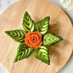 a flower made out of cucumbers and leaves on a cutting board with text overlay