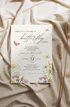 there is a wedding card on the bed with flowers and butterflies in front of it