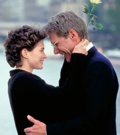 a man and woman embracing each other in front of water