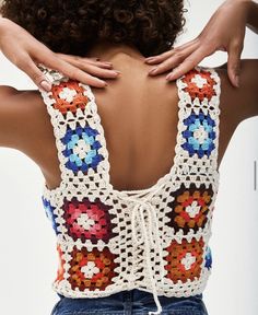 a woman with her back to the camera wearing a crocheted top and jeans