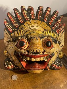 a wooden table with a mask on top of it and a coin in front of it