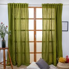 a room with green curtains and pillows on the floor