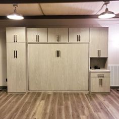 an empty room with wooden floors and cabinets