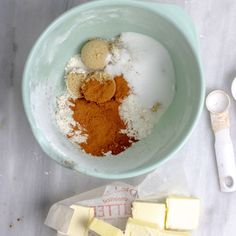 a bowl filled with different types of food next to butter and spoons on a table