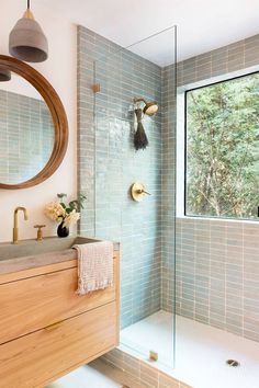 a bathroom with a sink, mirror and shower stall in front of a large window