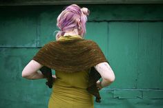 a woman with pink hair wearing a brown shawl over her shoulders and back to the camera