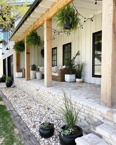 two black planters sitting on the front porch of a white house with stone steps leading up to it