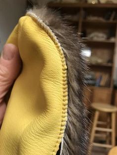 a close up of a person's hand holding a yellow cloth with fur on it